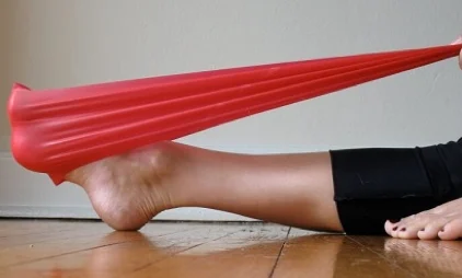 Seated with leg straight, a resistance band looped around the ball of the foot, pulling the toes back towards the body
