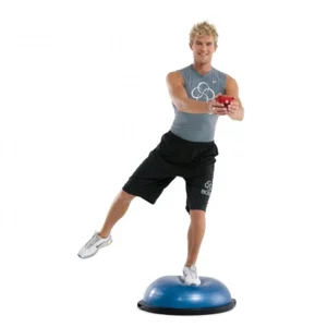 Man balancing on one leg on a BOSU ball, other leg reaching out to the side, holding a ball at chest height