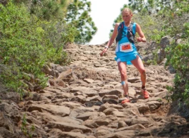 Trail runner descending a steep, rocky downhill path with short, controlled steps