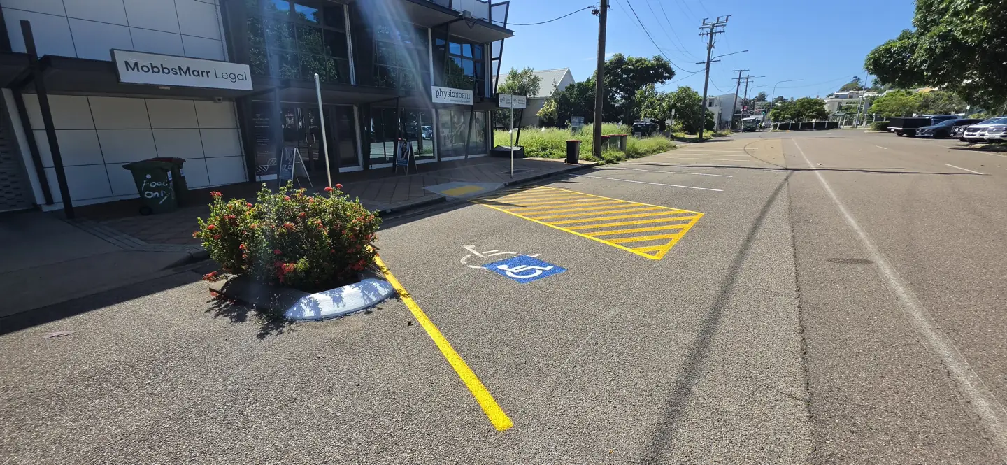 Accessible parking bay with a blue wheelchair symbol and yellow shared zone outside the Physionorth entrance on Eyre Street, North Ward, with a kerb ramp to the footpath