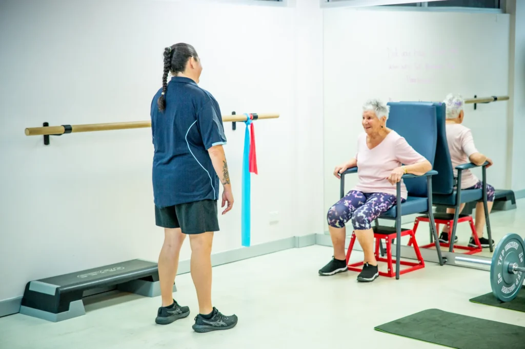 An older patient doing a seated exercise in a balance class