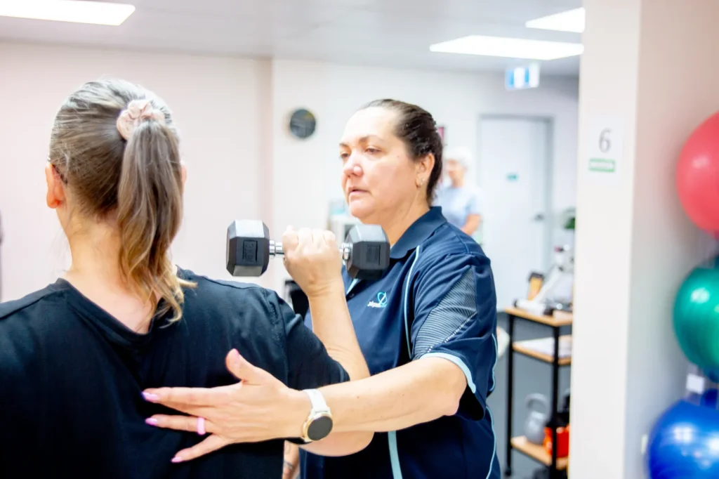 An exercise physiologist coaching a patient with a dumbbell