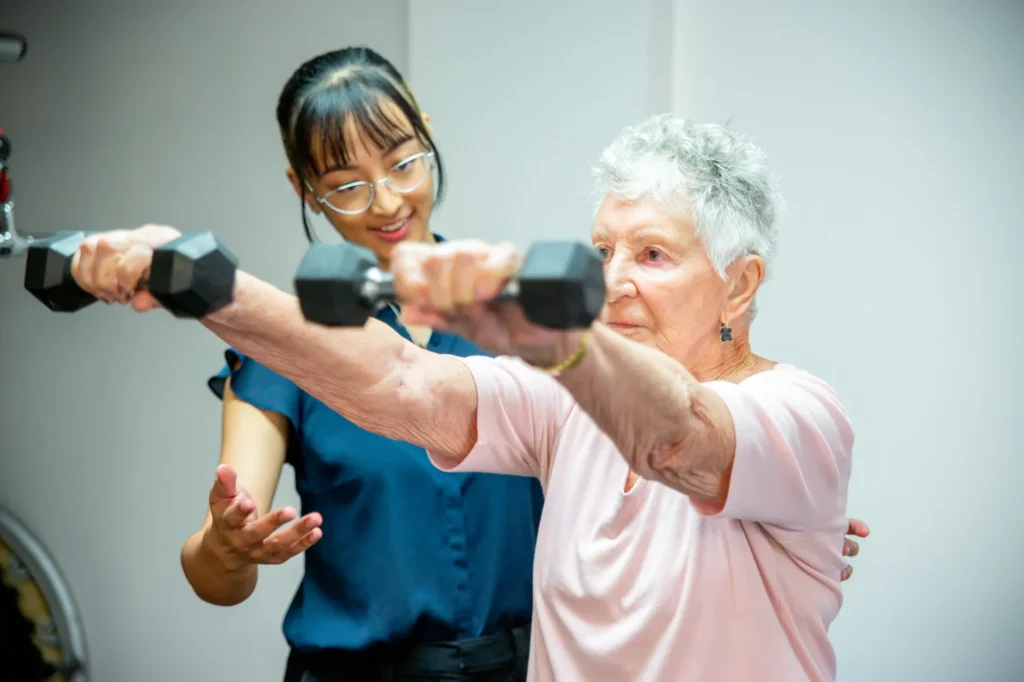 Exercise physiology in the clinic gym: an older patient lifting dumbbells with support