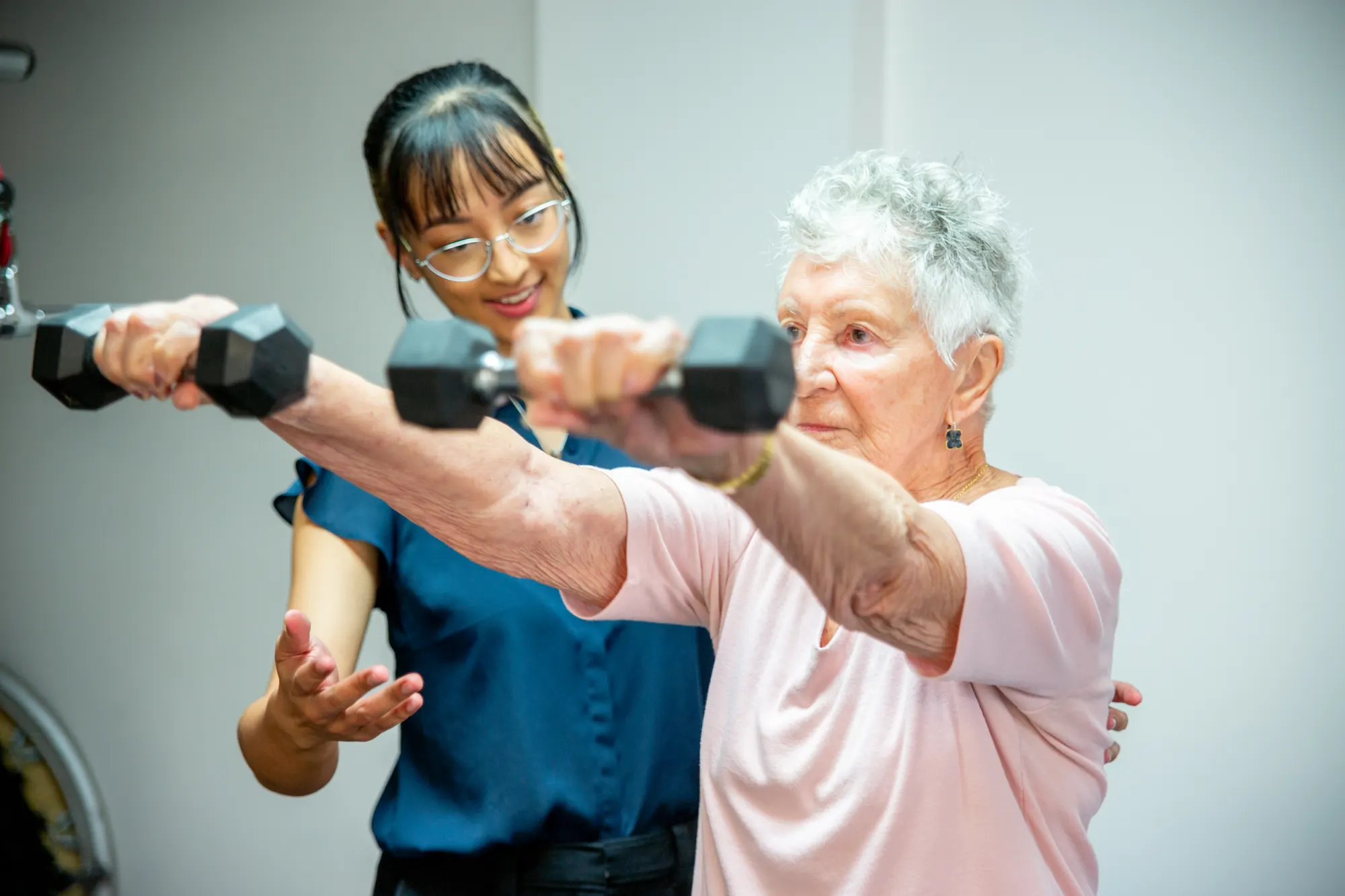 Exercise physiology in the clinic gym: an older patient lifting dumbbells with support