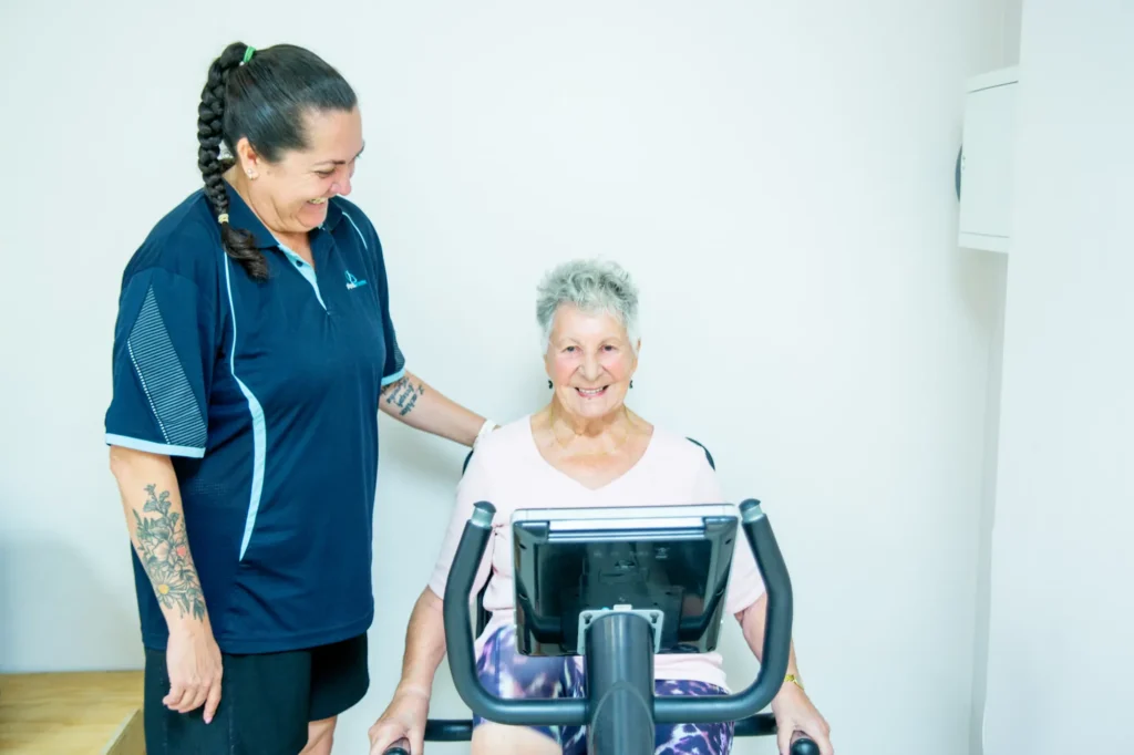 An exercise physiologist with an older patient on an exercise bike