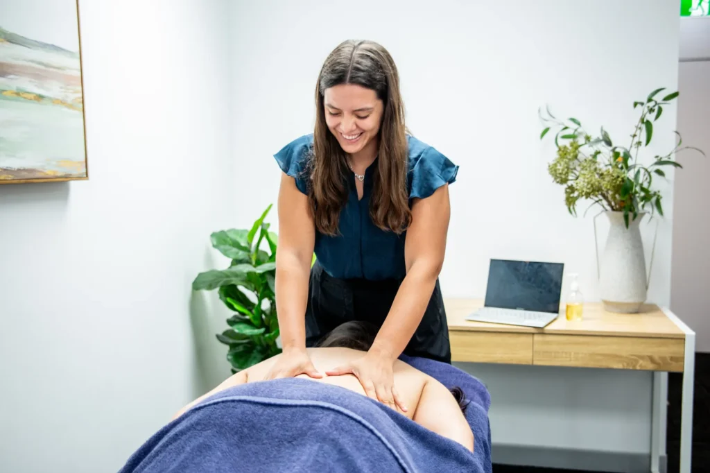 A massage therapist working firmly through a patient’s upper back