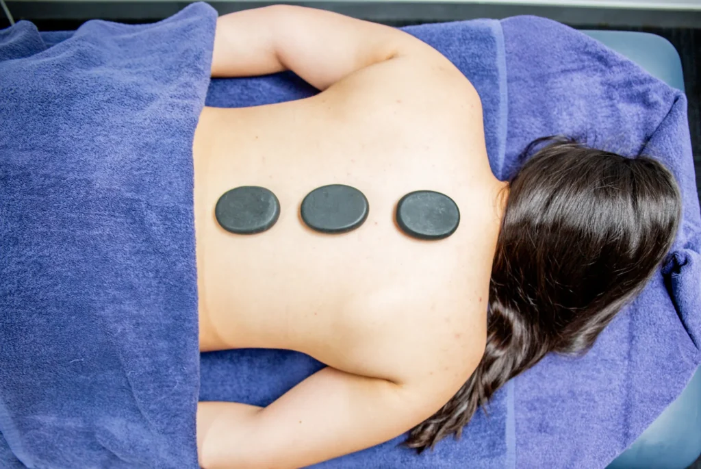Hot stones on a patient’s back during a remedial massage
