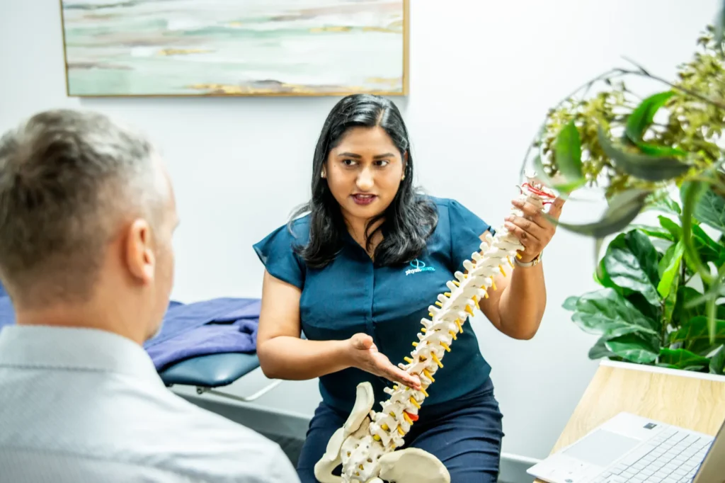 A physiotherapist explaining the spine to a patient using a model