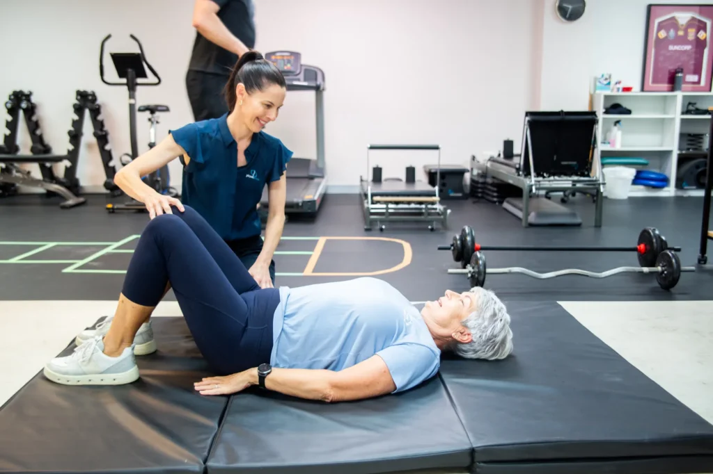 A physiotherapist helping an older patient with a mat exercise