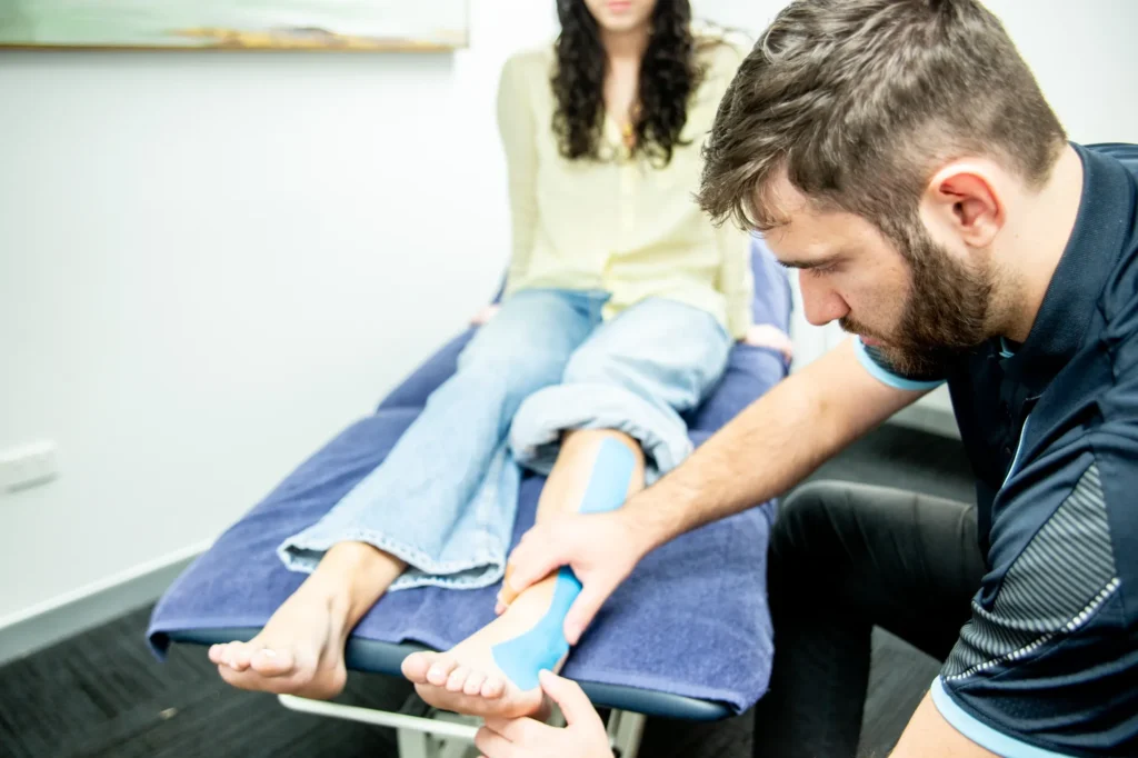 A physiotherapist taping a patient’s ankle